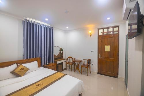 a bedroom with a bed and a table and a door at Khách sạn Ngọc Anh in Long Hai
