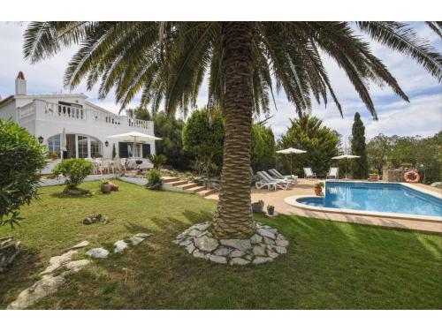 a palm tree in front of a house with a swimming pool at Alaior Villa with Private Pool in Alaior