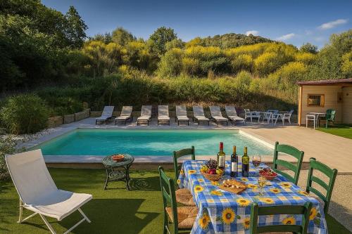 a table with wine bottles on it next to a swimming pool at Panoramic View Village of Villa Luigina Cortona in Castiglion Fiorentino