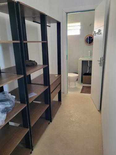 a bathroom with wooden shelves and a toilet at Casa Vento e Mar in Japaratinga