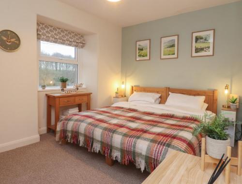 a bedroom with a bed and a table and a window at Willow Wood in Settle