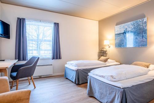 a hotel room with two beds and a desk at Højmølle Kro in Eskilstrup