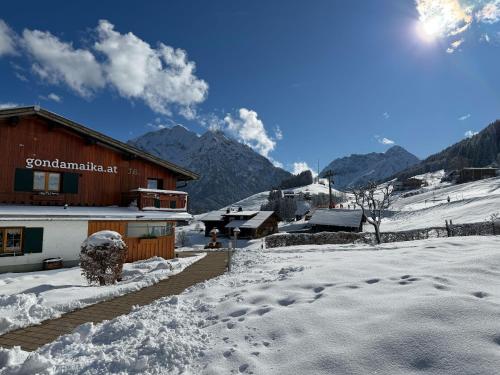 a snow covered village with a building and mountains at Bi-dr-Gondamaika in Hirschegg