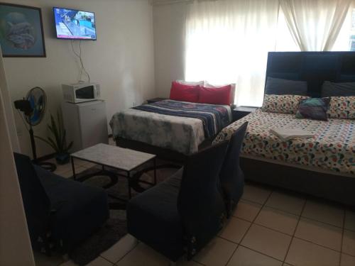 a small room with two beds and a table at Matte Guest House in Potchefstroom