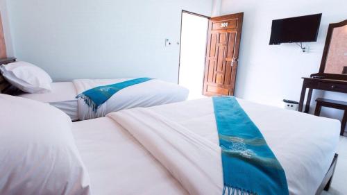 a hotel room with two beds and a television at Benya Hotel โรงแรมเบญญา in Nan