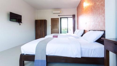 a bedroom with a large white bed and a television at Benya Hotel โรงแรมเบญญา in Nan