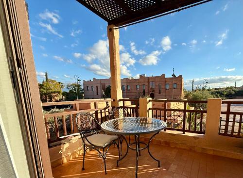 a table and chairs on a balcony with a view at Beach Mama Waky Marrakech Appartement Premium Piscine & Vue Atlas in Marrakesh