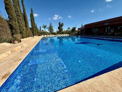 a large blue swimming pool with trees in the background at Beach Mama Waky Marrakech Appartement Premium Piscine & Vue Atlas in Marrakesh