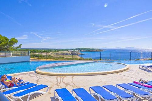 a swimming pool with lounge chairs and the ocean at Camping l'Arquet - Mobil-home Premium 4 pièces 6 personnes climatisé MAE-3771 in Martigues