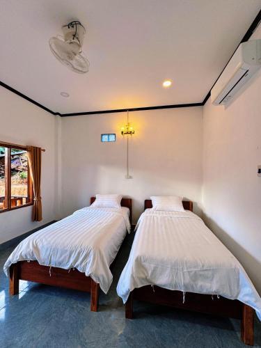 two beds in a room with white walls at phoulisack2 guesthouse in Nongkhiaw