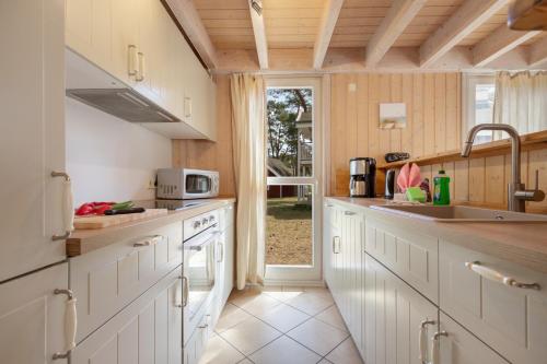 a kitchen with white cabinets and a sink and a window at Dünenblume - Baabe in Baabe