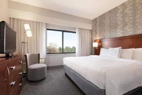 a hotel room with a bed and a television at Courtyard Charlotte Airport North in Charlotte