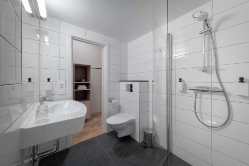 a white bathroom with a sink and a toilet at Scandic Södertälje in Södertälje