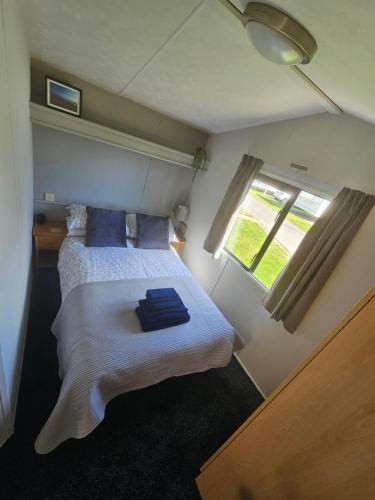 a bedroom with a bed with blue pillows and a window at Westfield 75 in Skipsea