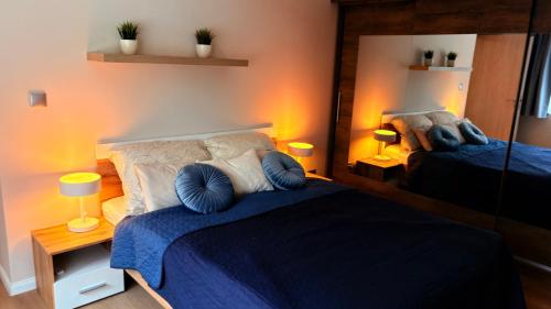 a bedroom with a blue bed and a mirror at Castello Rosso Apartman in Pilisvörösvár