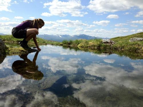 a woman is reflecting in a body of water at Vålådalens Fjällstation in Vålådalen