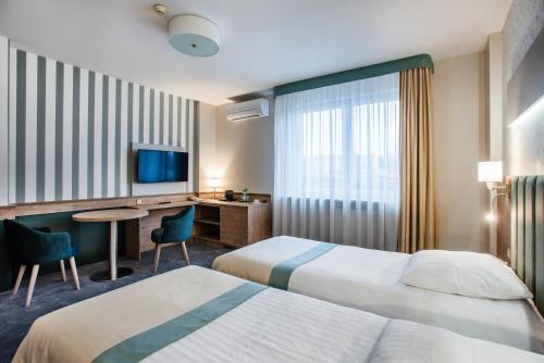 a hotel room with two beds and a desk at Hotel La Mar in Kielce