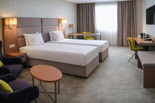 a hotel room with a bed and a desk and chairs at Hotel Golden Tulip Varna in Varna City