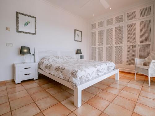 a white bedroom with a bed and a chair at Villa in Cala Llonga near Beach & Ferry Port in Cala Llonga