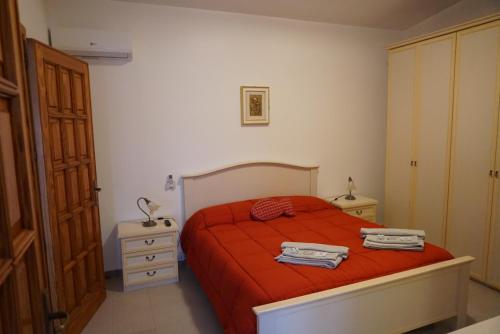 a bedroom with a bed with red sheets and a dresser at Molentargius Domus in Quartu SantʼElena
