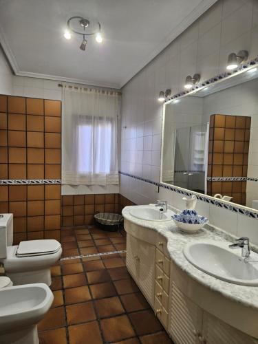 a bathroom with two sinks and a toilet and a mirror at Casa Rural El Hollejo in Pulgar