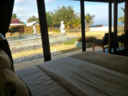 a bedroom with a bed and a view of a pool at Jepara Marina Beach Bungalows in Jepara
