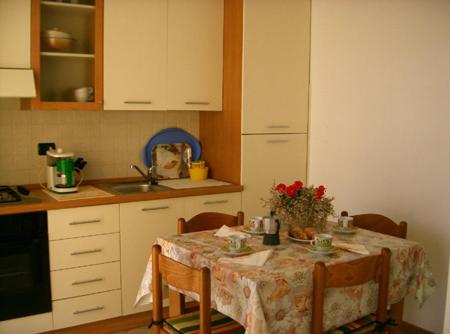 a kitchen with a table with chairs and a sink at Appartamenti Maria Grazia in Dongo