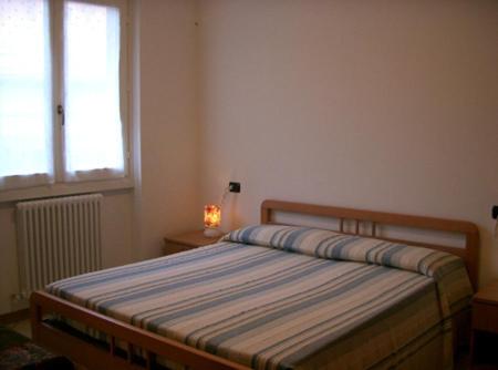 a bedroom with a bed and a window and a lamp at Appartamenti Maria Grazia in Dongo