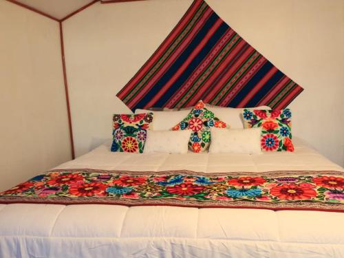 a bed with a colorful blanket and pillows on it at TiticacaIntiLodge in Puno