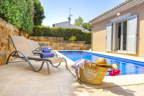 a pool with a chair and a basket next to it at Villa Synera in Alcudia
