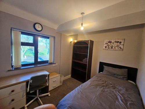 a bedroom with a bed and a desk and a clock at Little puppy in Birmingham