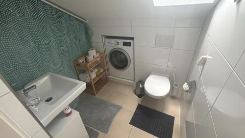 a bathroom with a sink and a washing machine at Bright attic apartment with charm in Sargans