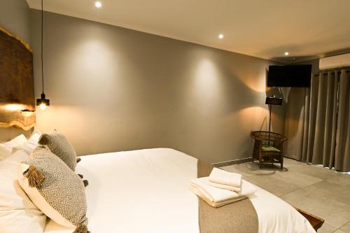 a bedroom with a white bed and a chair at The Roaming Goat Guesthouse in Toekoms