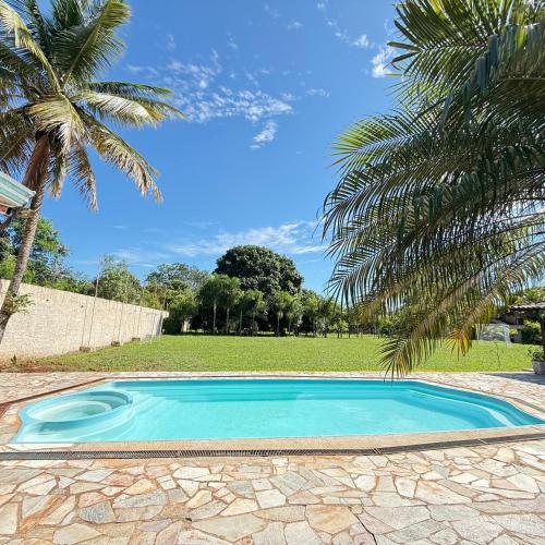 a small blue swimming pool next to a palm tree at Chacara Italia in Uberaba