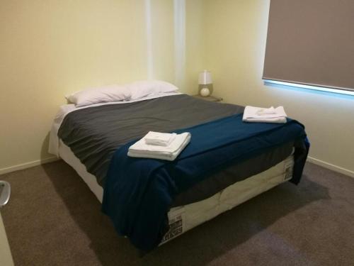 a bedroom with a bed with two towels on it at DatePalm CBD & Central Akl in Auckland