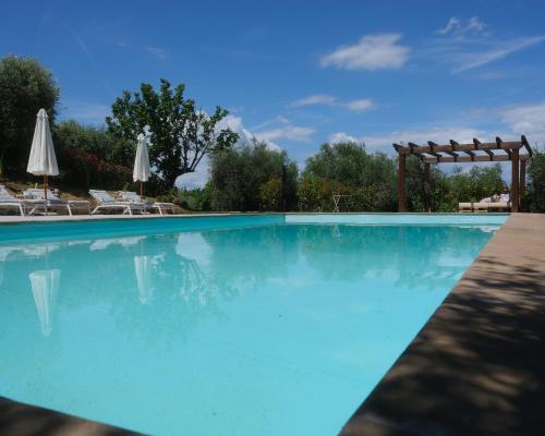 a swimming pool with chairs and umbrellas at Casal di Peppe B&B in Lorenzana