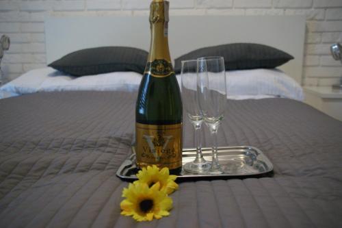 Una botella de vino y dos copas en una cama. en Apartamenty Viniarnia, en Zielona Góra