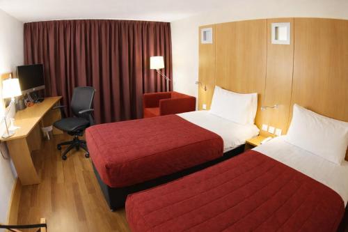 a hotel room with two beds and a desk and a chair at Station House Hotel Letterkenny in Letterkenny