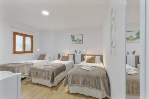 three beds in a room with white walls and wooden floors at TeXeda Room Suites in Tejeda