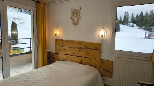 a bedroom with a bed and a large window at Le Repaire du Loup blanc in Prémanon