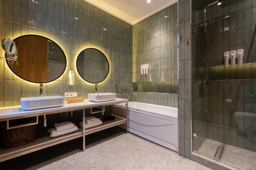 a bathroom with two sinks and a tub and mirrors at IGMAR Villas & Aparts Hotel in Tashkent