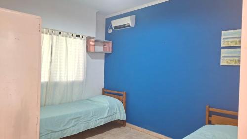 a blue room with two beds and a window at Chacra Arcoiris in Gualeguay