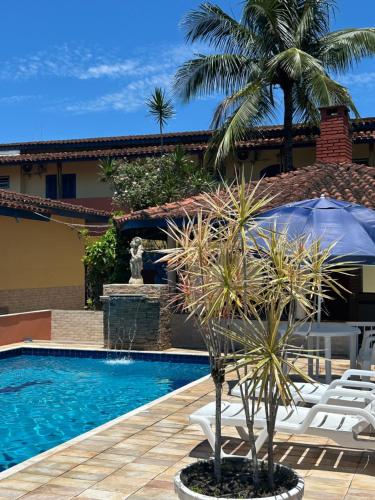 a pool with chairs and a palm tree next to a house at Villa Di Verona Charm Hotel in Guarujá
