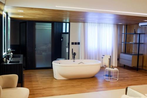 a bathroom with a large white bath tub on a wooden floor at Hotel Pedra Negra Gov. Valadares in Governador Valadares