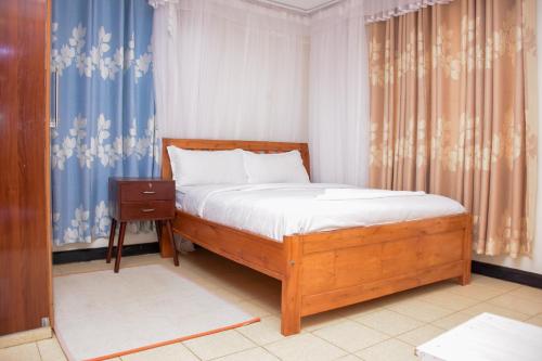 a bedroom with a bed with a wooden frame and curtains at The π Homes in Eldoret