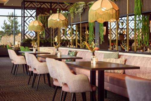 a restaurant with tables and chairs and chandeliers at Farm house Van der Valk Hotel Leeuwarden in Leeuwarden