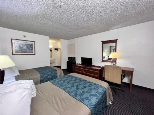 a hotel room with two beds and a desk at Heritage Inn & Suites by Capital O Baton Rouge I 10 in Baton Rouge
