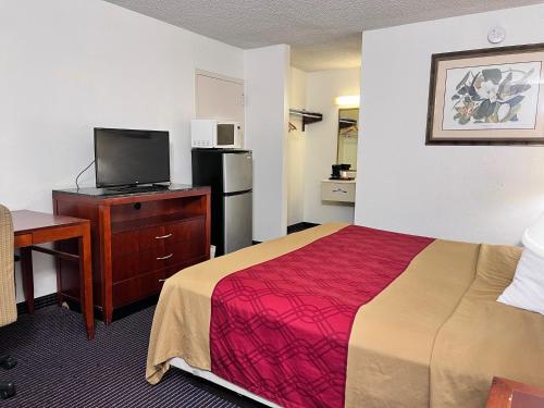 a small hotel room with a bed and a tv at Heritage Inn & Suites by Capital O Baton Rouge I 10 in Baton Rouge