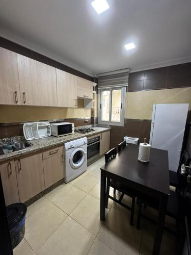 Una cocina con una mesa, una estufa y un refrigerador. en Fnideq Seaside Apartment, en Fnidek