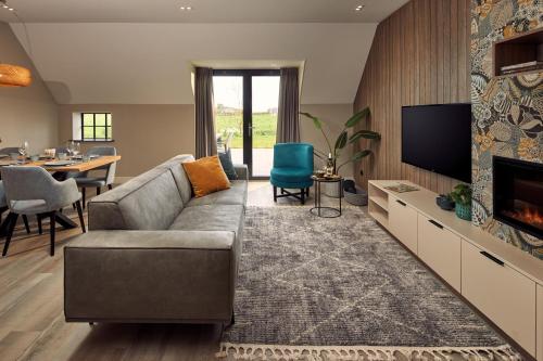 a living room with a couch and a tv at Farm house Van der Valk Hotel Leeuwarden in Leeuwarden